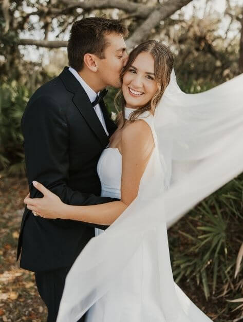 bride and groom hugging her veil blowing in the wind