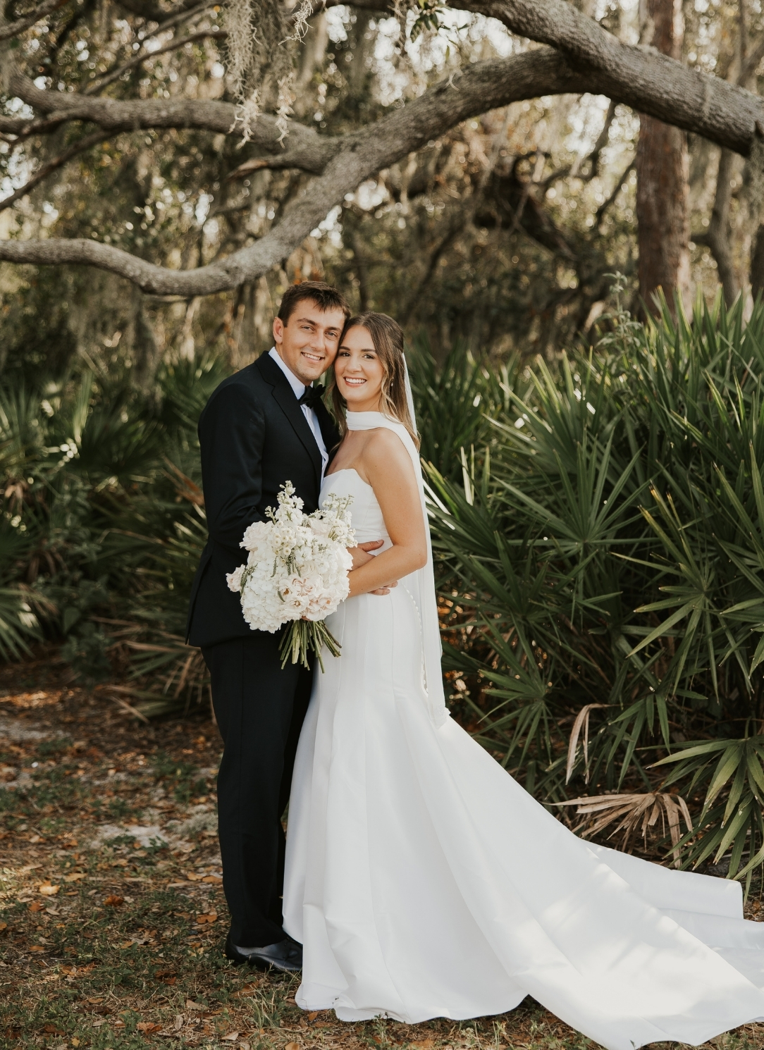 bride and groom posing in front of a tree
